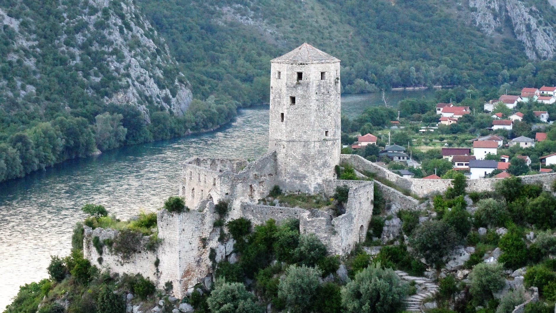 aerial picture of gray stone tower beside river and town