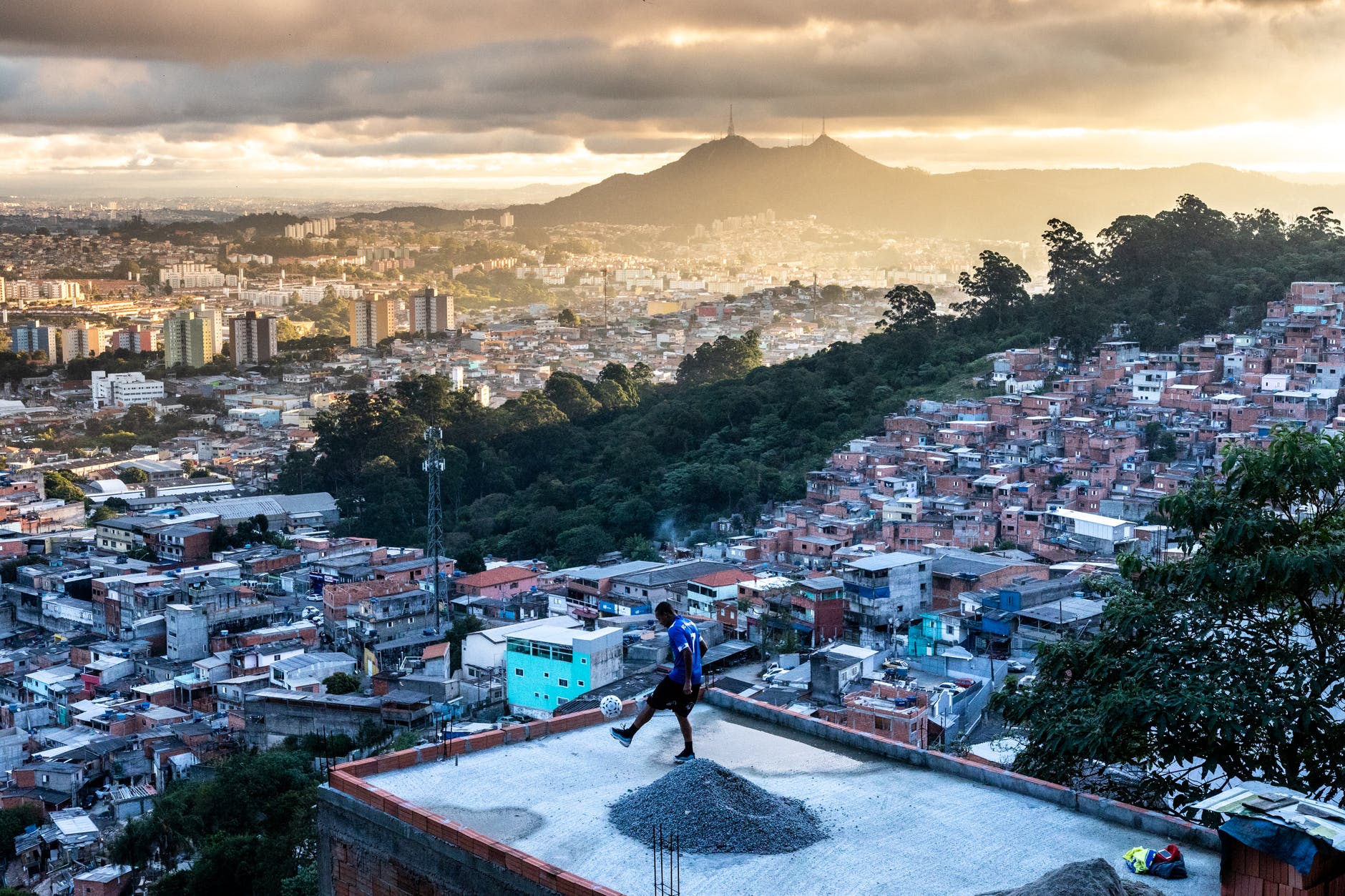 man playing football on rooftop across the city