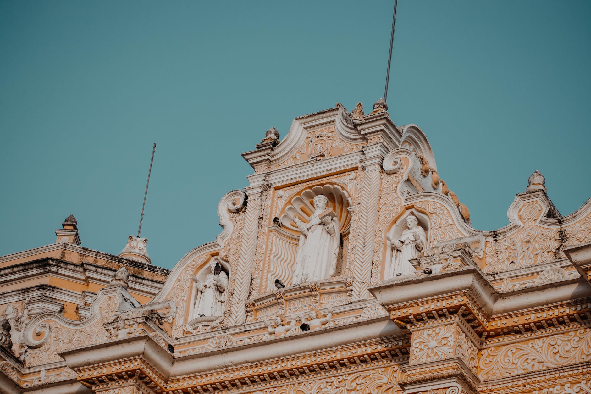 brown church with statues under blue sky