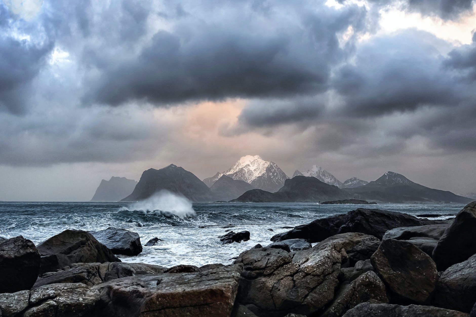 waves crashing on rock near mountains during datyime