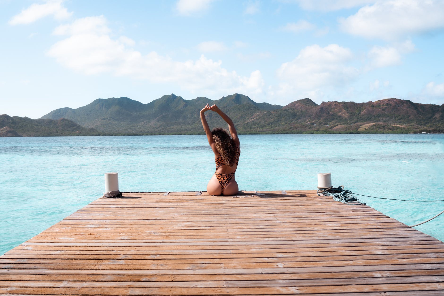 woman in black and brown bikini sitting on brown wooden dock